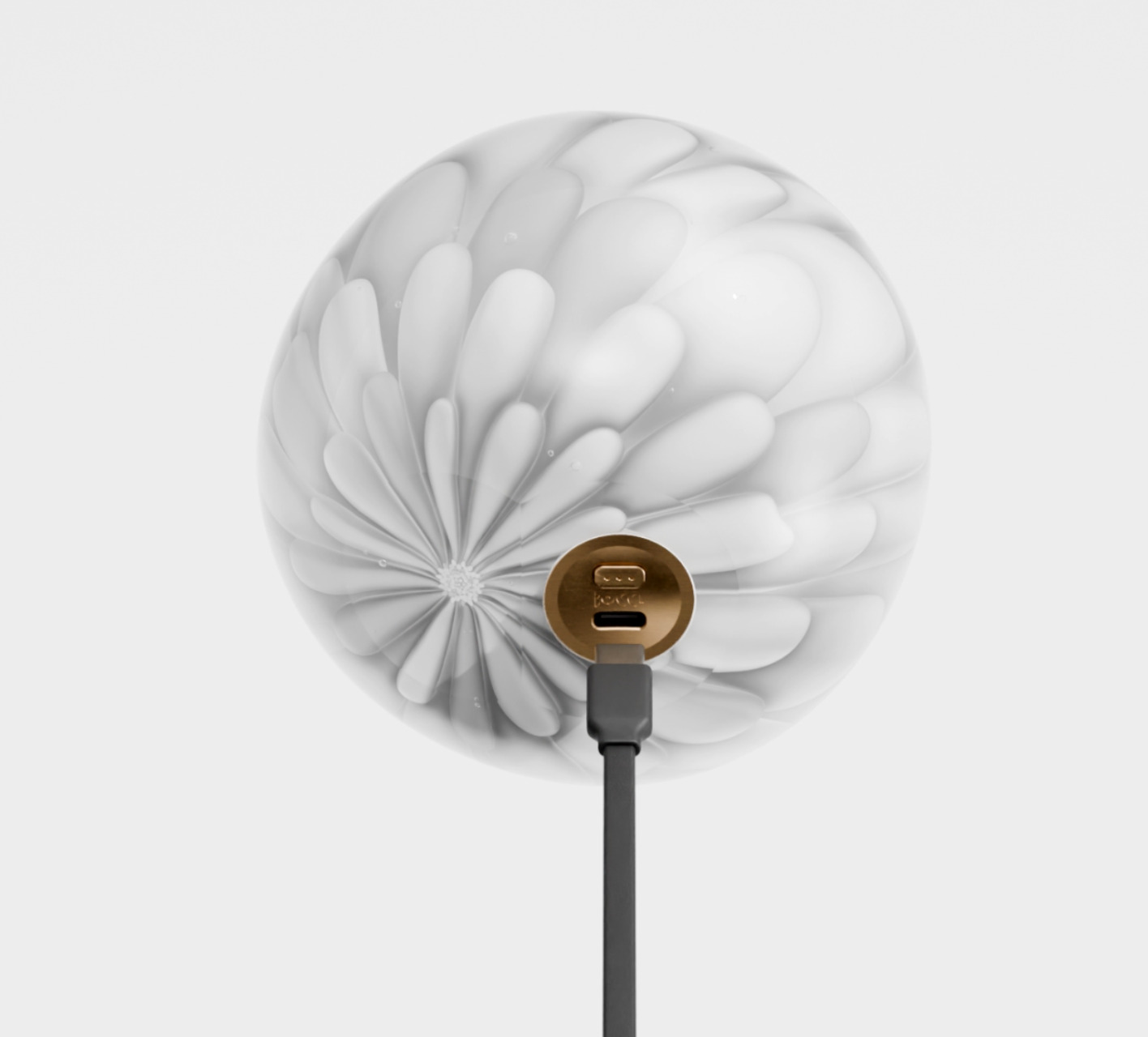 Underside of the Bocci petal glass pendant with the brass charging port exposed and cable connected